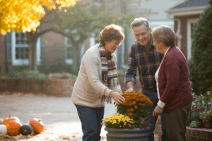 a senior living courtyard in early fall, showing a small group of two or three senior residents wearing cozy, autumn-appropriate clothing